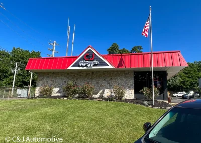 Exterior view of C&J Automotive & Tire of Berwyn, showing an attractive building with nice lawn and an American flag.