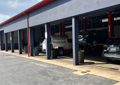 Row of open service bays at C&J Automotive with a variety of vehicles.