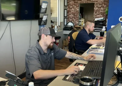 Staff at C&J Automotive assisting customers over the phone and computer in a modern office.