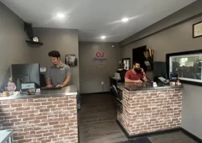 Two staff members assisting customers at the front desk of C&J Automotive Specialists.