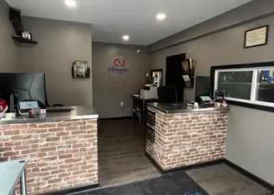 Front desk area at C&J Automotive featuring a service desk and reception area and a branded floor mat with the company name.