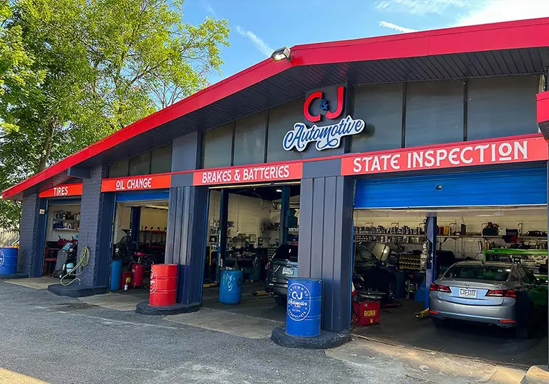 C&J Automotive in Newtown Square with open service bays for tires, oil changes, brakes and batteries, and state inspections, showing vehicles and automotive equipment inside the shop.