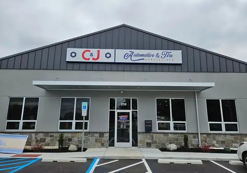 C&J Automotive & Tire Specialists in Sewell featuring a modern gray storefront with a large branded sign, glass entrance, and parking spaces.